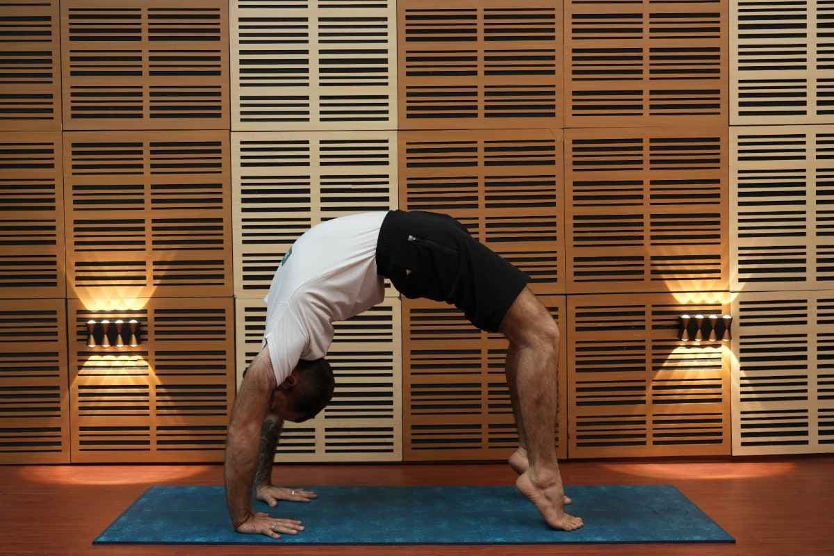 Professeur de yoga réalisant la posture de la roue lors d'une séance de yoga